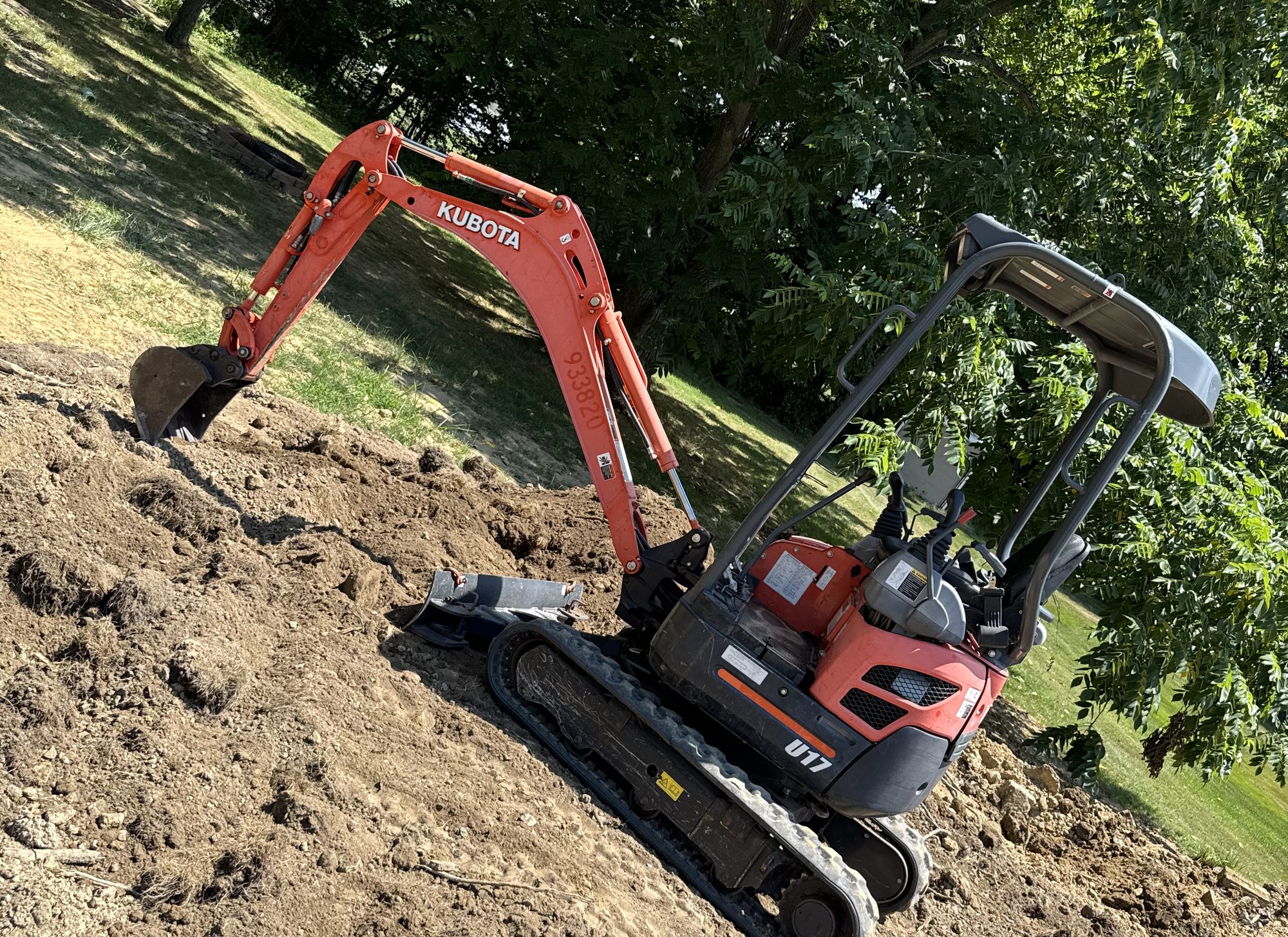 Mini excavator grading a sloped residential yard